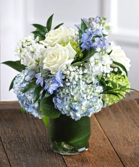 Elegant bouquet of white roses and blue hydrangeas arranged in a crystal vase