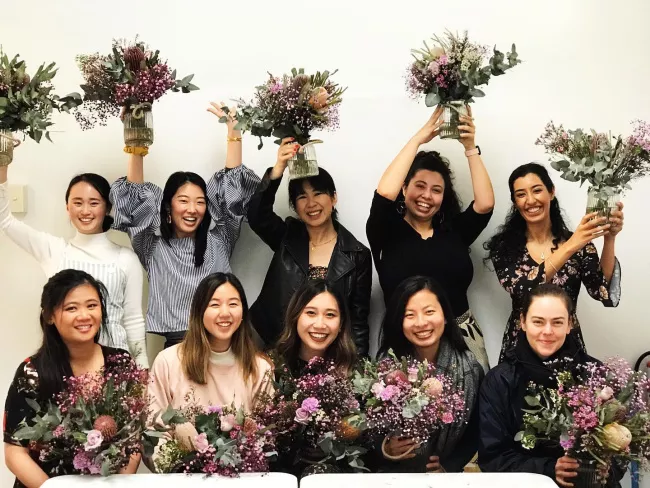 The Petals & Pines team smiling together in the shop surrounded by beautiful floral displays