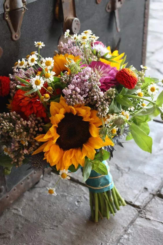 Vibrant mixed bouquet featuring sunflowers, daisies, and wildflowers in rustic wrapping
